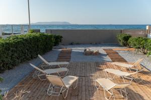 un grupo de sillas sentadas en un patio cerca del océano en Aelia seafront house en Kokkíni Khánion