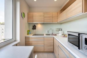 a kitchen with wooden cabinets and a microwave at Apartament Sweet in Gdynia
