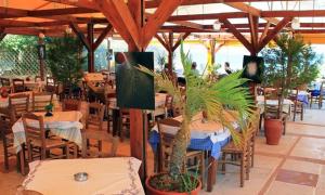 a restaurant with tables and chairs and potted plants at Calypso Hotel Apartments in Kato Daratso