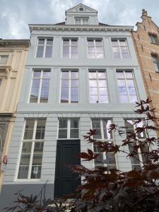 een hoog wit gebouw met een zwarte deur bij Maison Brunon in Brugge