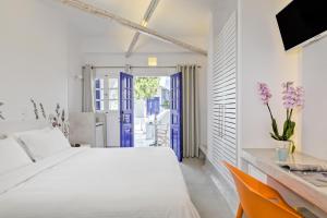 a white bedroom with a white bed and a blue door at Kouros Village Hotel - Adults Only in Perissa +37 photos