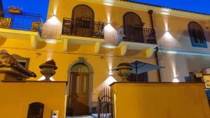 - un bâtiment jaune et blanc avec fenêtres et balcons dans l'établissement Sa Benedica - Luxury House, à Calatabiano