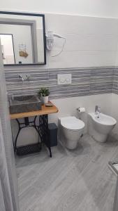 un bagno con lavandino, water e specchio di Sa Benedica - Luxury House a Calatabiano Altre 35 foto