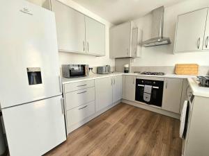 a white kitchen with white appliances and wooden floors at Entire house, Waterloo, free street parking in Waterloo +16 photos