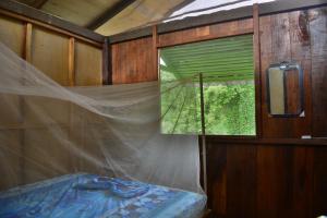 - une chambre avec une fenêtre et un lit avec une moustiquaire dans l'établissement Posada Nativa El Esfuerzo 2, à Nuquí