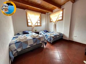 two beds in a room with two windows at Hostal Dulces Sueños in Panajachel