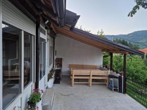 eine Terrasse mit einer Holzbank an der Seite eines Hauses in der Unterkunft Zavojsko jezero - kuća Mitić in Pirot