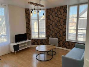 a living room with a table and a tv at Le Saint Joseph in Chalons en Champagne