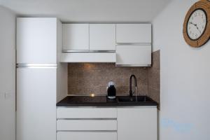 a kitchen with white cabinets and a clock on the wall at Porto Rotondo loft sul porto in Porto Rotondo