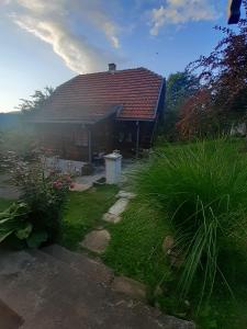 ein Haus mit rotem Dach und Gras in der Unterkunft Kuća za odmor Kalina in Mokra Gora