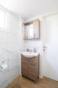 a white bathroom with a sink and a shower at Volos Horizon Oasis Apartment #1 in Volos