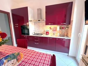 eine Küche mit roten Schränken, einer Spüle und einem Tisch in der Unterkunft Royal Domus Of Rome in Rom