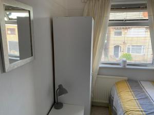 1 dormitorio con cama, espejo y ventana en Hadfield Avenue en Hoylake