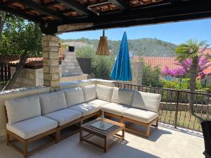 a patio with a couch and a table and a blue umbrella at Holiday House Mia in Ražanj