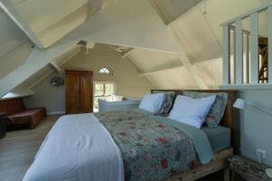 a bedroom with a large bed in an attic at Het Betuws Erfje in Maurik