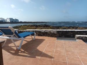 a chair sitting on a patio next to the ocean at casa el lajiar in Orzola