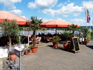un patio con mesas, sombrillas y palmeras en Hotel Rheinischer Hof en Bad Breisig