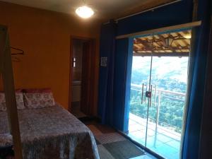 a bedroom with a bed and a large window at Pousada Quiosque do Professor in Macacos