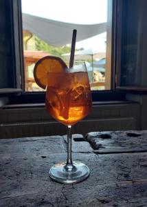 una bebida en un vaso con una rodaja de naranja en él en fragole e menta, en Attimis