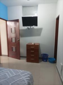 ein Schlafzimmer mit einem Bett und einem TV an der Wand in der Unterkunft Emmanuel&Cavita in Iquitos