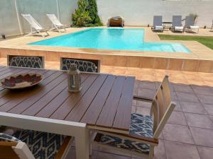 uma mesa de madeira e cadeiras ao lado de uma piscina em Chalet con encanto cerca de Sevilla em Alcalá de Guadaíra