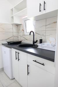 a kitchen with white cabinets and a sink at Apartmani Hedonist in Soko Banja