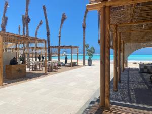 - un restaurant sur la plage avec des palmiers et l'océan dans l'établissement MARASSI Marina west ll 1BR 3BD near of SOL beach, à El Alamein