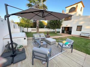 a patio with an umbrella and chairs and a grill at Chalet con encanto cerca de Sevilla in Alcalá de Guadaira