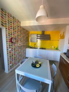 une cuisine avec une table et des chaises et un mur jaune dans l'établissement Casa di GEF [Centro Storico Pisa], à Pise