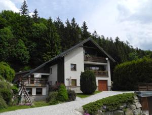 a white and black house with a balcony at Apartmány Müller in Bedřichov