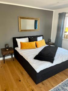 a bed with orange and black pillows in a bedroom at UNiQE I 90qm I Terrasse in Rosenheim