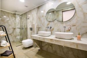 łazienka z 2 umywalkami i prysznicem w obiekcie Oasis Deluxe Studios w mieście Pefkari