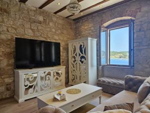 a living room with a tv on a stone wall at Luxury Seafront Suite Fabri in Vis