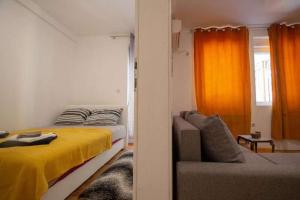 - une chambre avec un lit jaune et un canapé dans l'établissement Centar stan na dan za do 4 osobe, à Novi Sad