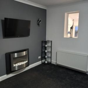 a living room with a fireplace and a flat screen tv at J & S Apartments in Ayr