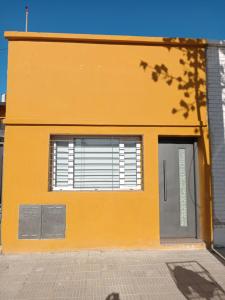 a yellow building with a door and a window at Departamentos pura vida 2 in General Roca