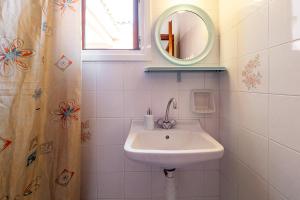 uma casa de banho branca com um lavatório e um espelho em XENOFONTAS APARTMENTs em Agios Georgios Pagon