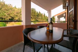 uma mesa com uma garrafa de vinho na varanda em XENOFONTAS APARTMENTs em Agios Georgios Pagon