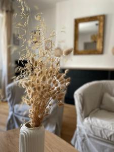 a white vase with dried flowers on a table at Le Cosy in Blois