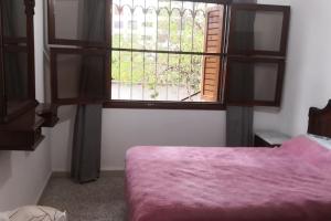1 dormitorio con ventana y 1 cama con manta rosa en Casa Mima, en Tetuán