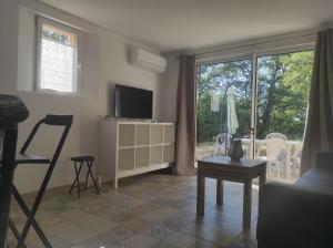 a living room with a tv and a table and a window at Les quatre chênes in Bauduen