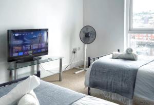 1 Schlafzimmer mit 2 Betten, einem TV und einem Fenster in der Unterkunft Elegant and Bright Seaside APT in Swansea Marina in Swansea