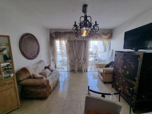 a living room with a couch and a chandelier at Charming Warm and Sun-Filled 1 and 2 Bedroom Apartment in Ashdod