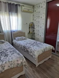 a bedroom with two beds and a window at Charming Warm and Sun-Filled 1 and 2 Bedroom Apartment in Ashdod