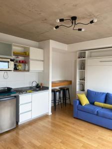 a living room with a blue couch and a kitchen at Monoambiente en La Boca. in Buenos Aires