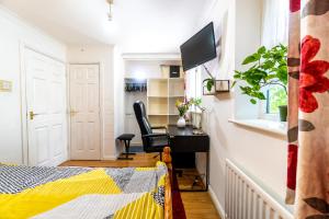 a bedroom with a bed and a desk and a television at Super room with free parking 400 Mbps Internet in London