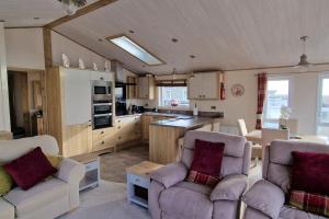 ein Wohnzimmer mit zwei Stühlen und eine Küche in der Unterkunft Sea View Lodge, Seal Bay Resort, Selsey in Selsey