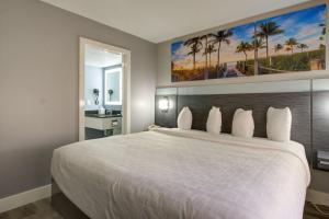 a bedroom with a large white bed with a painting on the wall at Clarion Pointe Tampa-Brandon Near Fairgrounds and Casino in Tampa