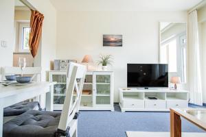 ヴェスターラントにあるApp-Rimmler-Suedstrandperleのリビングルーム(白い家具、テレビ付)