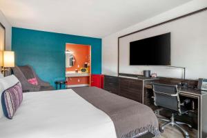 a hotel room with a bed and a desk with a television at Heights House Hotel, Ascend Hotel Collection in Houston